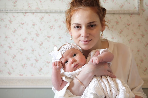 Pretty young mother holding a newborn daughter in her arms