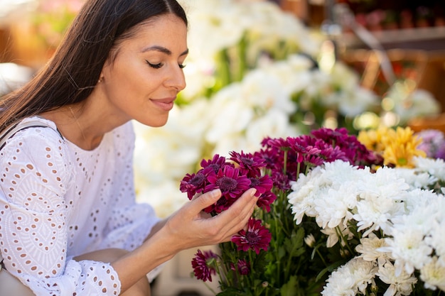 Pretty young woman buying flowers at the flower market