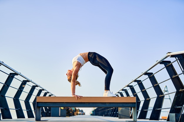 Pretty young woman doing yoga exercise on the nature in the morning