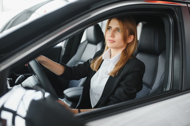 Pretty young woman driving her new car (color toned image; shallow DOF)