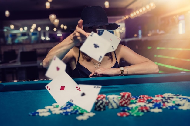 Pretty young woman in elegent blck dress gambling on casino green table