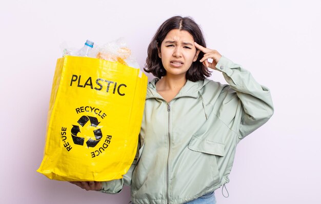 Pretty young woman feeling confused and puzzled, showing you are insane. plastic recycling concept