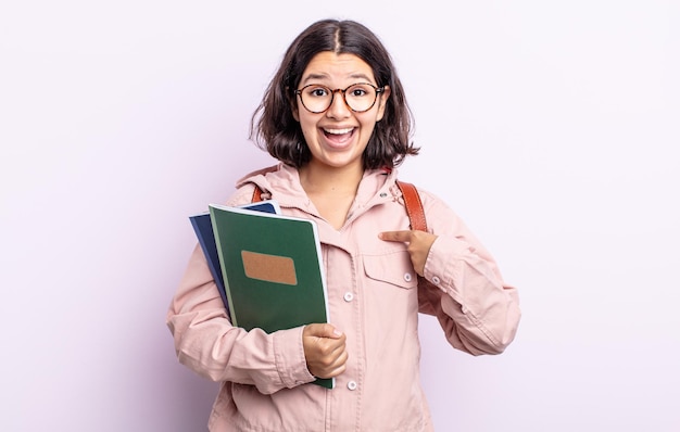 Pretty young woman feeling happy and pointing to self with an excited. student with books concept