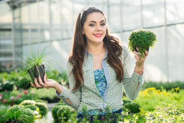 Pretty young woman gardener in the greenhouse among the flowers