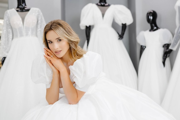 Photo pretty young woman is choosing a wedding dress in the shop the bridetobe is wearing a wedding dress for fitting