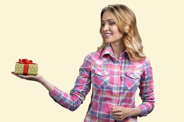 Pretty young woman looking at gift box in her palm