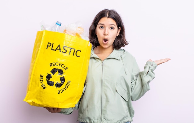 Pretty young woman looking surprised and shocked, with jaw dropped holding an object. plastic recycling concept