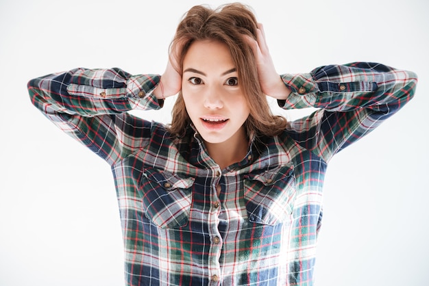 Pretty young woman in plaid shirt with hands on head