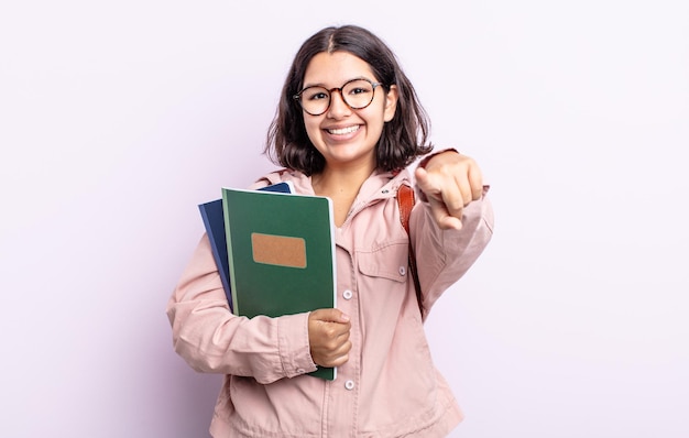 Pretty young woman pointing at camera choosing you. student with books concept