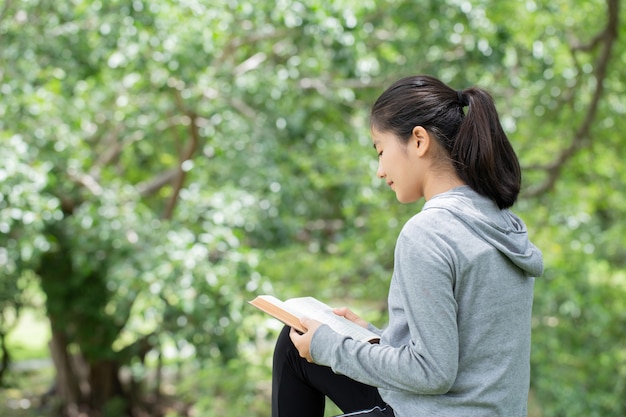 Pretty young woman reading bible in park. Reading a book. concept of God's bible is based on faith and spirituality.