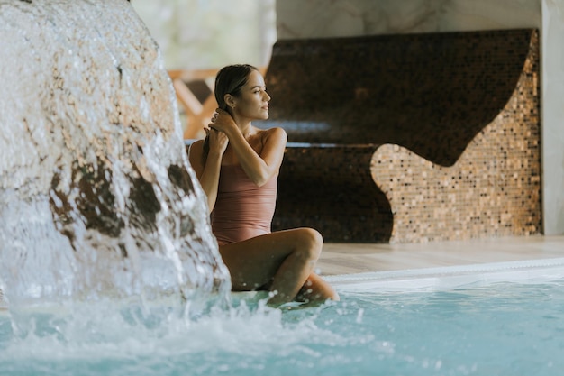 Pretty young woman relaxing by the indoor swimming pool