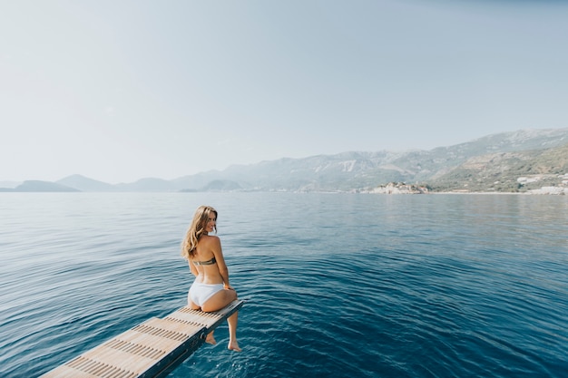 Pretty young woman relaxing on the yacht on sea at sunny day