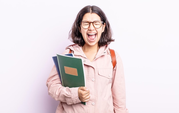 Pretty young woman shouting aggressively, looking very angry. student with books concept