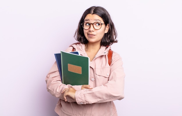 Pretty young woman shrugging, feeling confused and uncertain. student with books concept