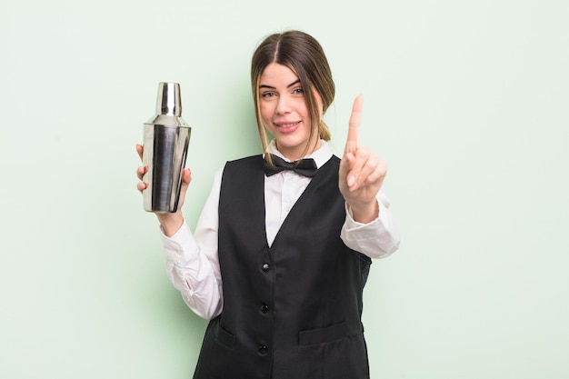 pretty young woman smiling proudly and confidently making number one. cocktail barman concept