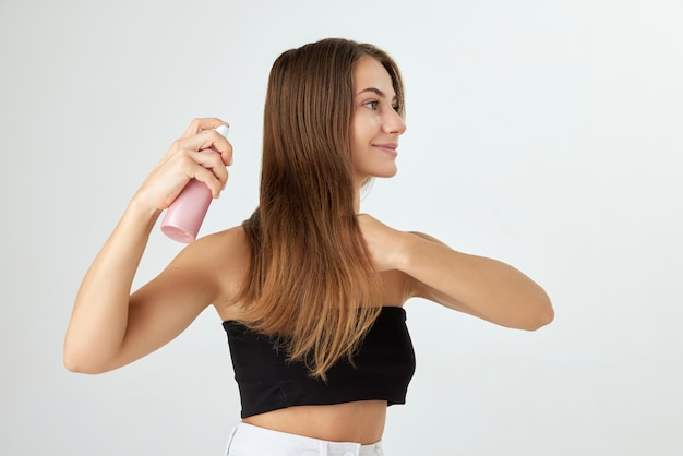 Pretty young woman taking care after health with spray isolated on white background glowing hair