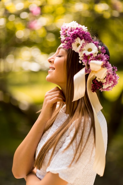 Pretty young woman with flowers in her hair on sunny spring day