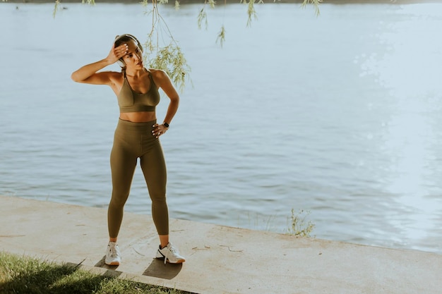 Pretty young woman with headphones taking a break during exercising outside