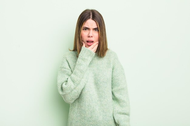 Pretty young woman with mouth and eyes wide open and hand on chin