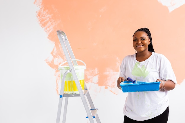 Pretty young woman with painting roller indoors