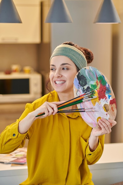 A pretty young woman with a palette and brushes in hands