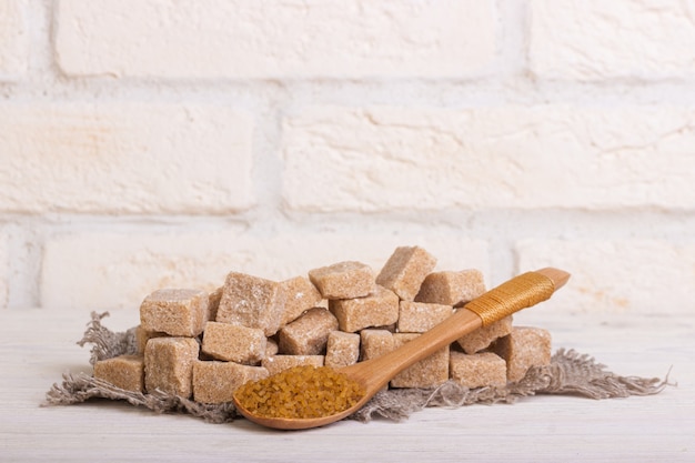 Pricked cane sugar in cubes on a linen cloth and a wooden spoon