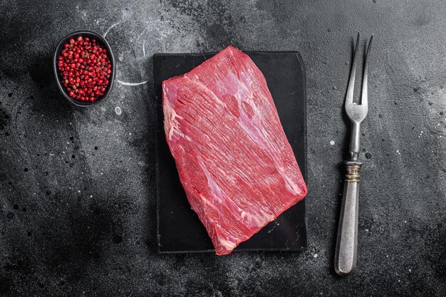 Photo prime choice flank steak raw beef meat on marble board with herbs black background top view