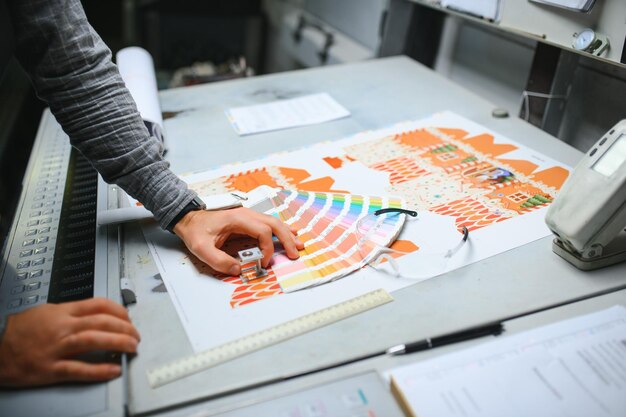 Photo print house worker controlling printing process quality and checking colors with magnifying glass