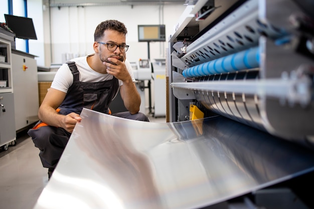 Print worker trying to fix the problem on computer to plate machine in printing shop.