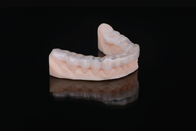 Printed transparent dental cap made of polymer on a light colorful background dental splint against