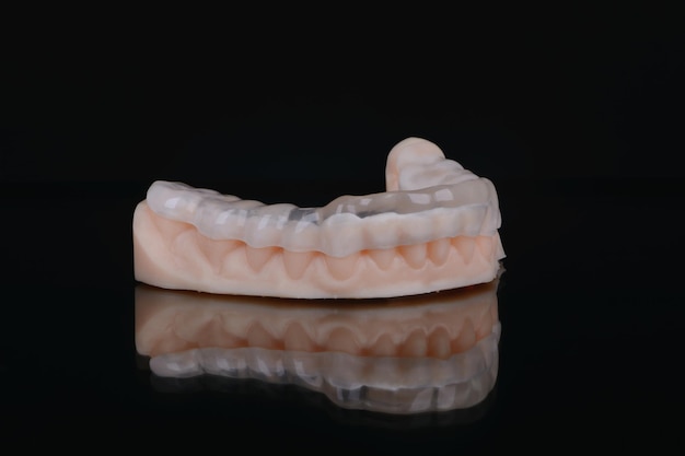 Printed transparent dental cap made of polymer on a light colorful background dental splint against