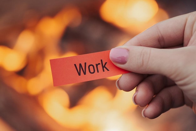 Printed word work on red small sheet of paper burning fire on background close up