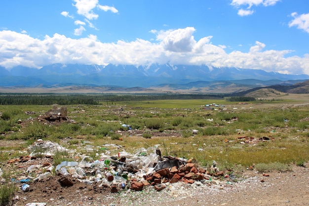 The problem of environmental pollution Garbage dump in a field near beautiful mountain ranges