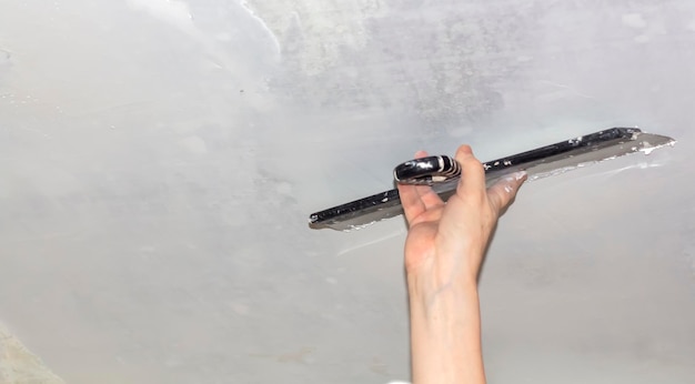 The process of applying mastic with a spatula to the surface to decorate the interior of the room Application of putty