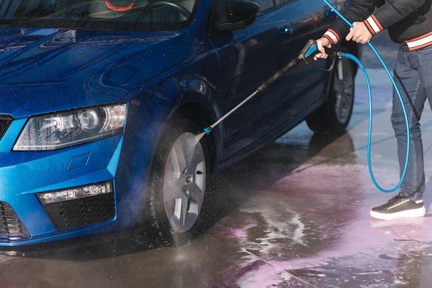 Process of cleaning car with a jet sprayer self service car washing closeup of man wash wheels