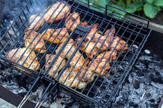 Process cooking meaty steak on a barbecue grill outdoors. Picnic, eating outdoors. Metal barbecue grill