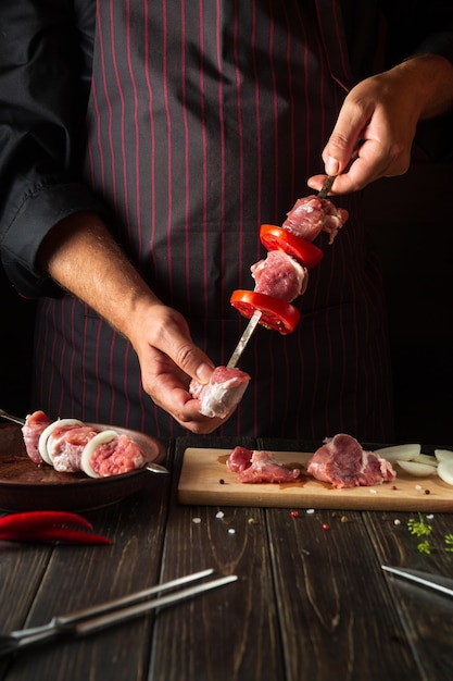 The process of cooking shish kebab from raw lamb meat in the kitchen with the hands of a chef