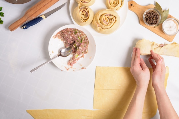 process of cooking Uzbek manti at home, the ingredients are meat, vegetables, dough. woman's hands sculpt manti.