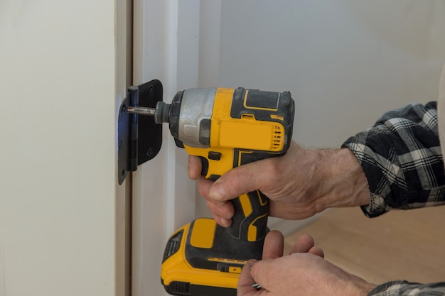 Process of installation stainless door hinges on a white wood door with screwdriver