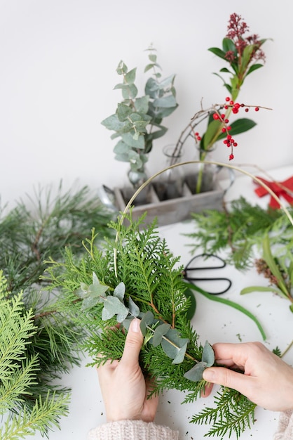 The process of making a Christmas wreath from needles thuja shimia rosehip pine twigs chopped twigs for the wreath The concept of preparation for Christmas and New Year