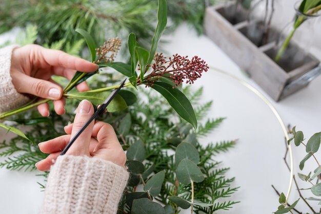 The process of making a Christmas wreath from needles thuja shimia rosehip pine twigs chopped twigs for the wreath The concept of preparation for Christmas and New Year