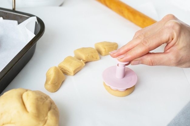 The process of making cookies with shapes in the form of flowers a rolling pin and a tray the concept of cooking baking at home