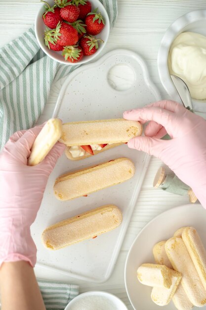 Photo the process of making a dessert of savoyard cookies strawberries and buttercream