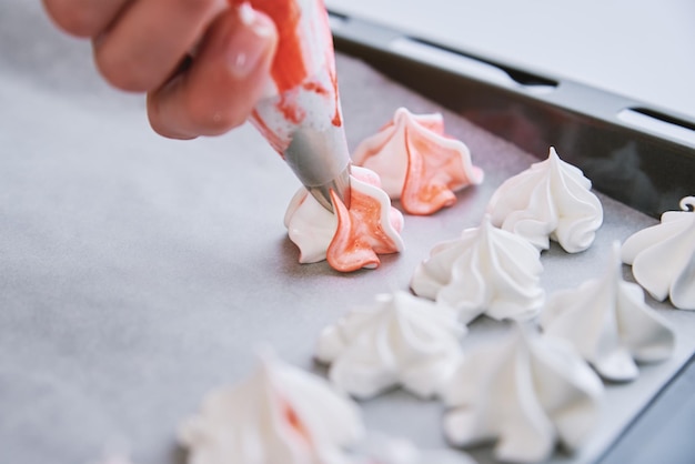 Process of making homemade meringue woman cooking sweet cream for dessert on baking sheet