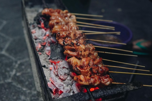 Photo the process of making indonesian chicken satay in traditional way using charcoal