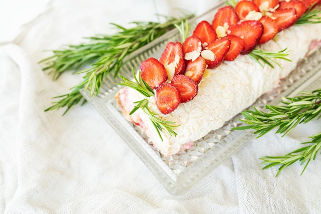 The process of making a meringue roll Cooking a meringue roll in the kitchen Meringue roll with strawberries and decorated with rosemary