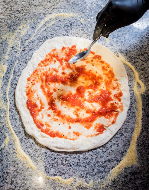 The process of making pizza. Hands of chef baker making pizza at cafe kitchen