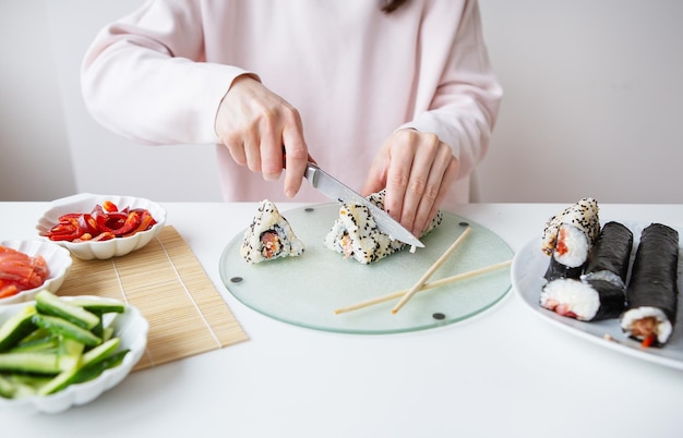 The process of making sushi the girl makes sushi with different flavors fresh salmon caviar avocado cucumber ginger rice Cut the roll into pieces