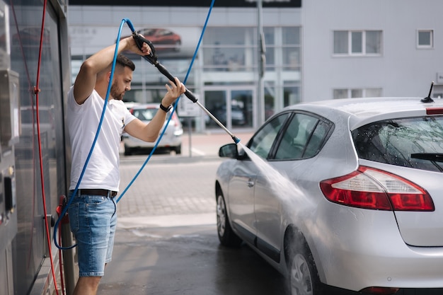 Process of man washing his car in a selfservice car wash station