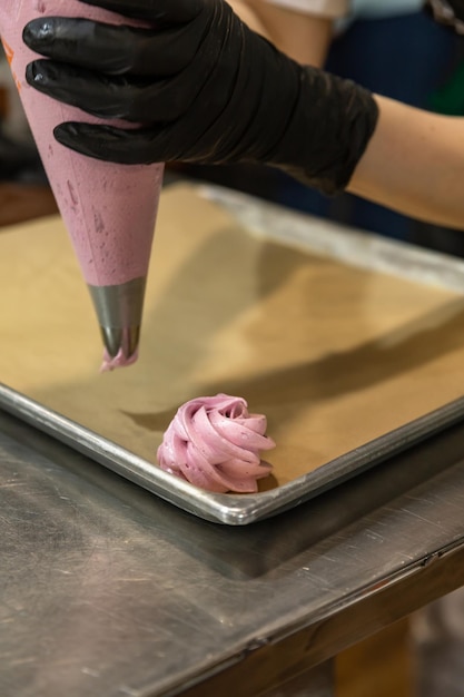 Process of marshmallow making Chef squeezing meringue dessert from pastry bag on baking sheet